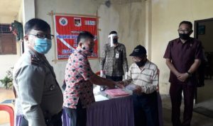 Camat Kawangkoan Utara Fabian Mendur,SPt,MM menyerahkan BLT kepada salah satu warga Kiawa Satu Utara.