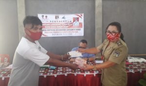 Hukumtua Masri Aruperes menyerahkan uang BLT dan masker kepada warga Desa Ampreng.