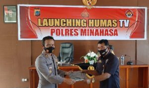 Kapolres Minahasa AKBP M Denny I Situmorang SIk simbolik menyerahkan pakaian seragam kepada redaktur pelaksana Humas TV Polres Minahasa Syaifudin Hadju.